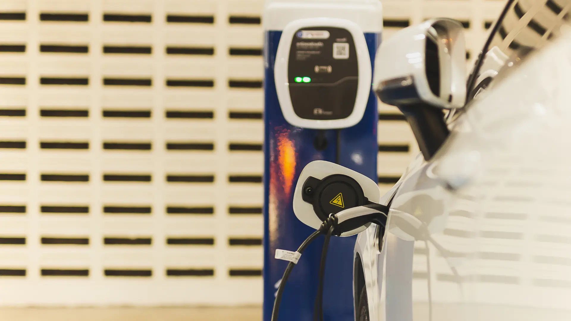 Automobil electric alb conectat la stație de încărcare