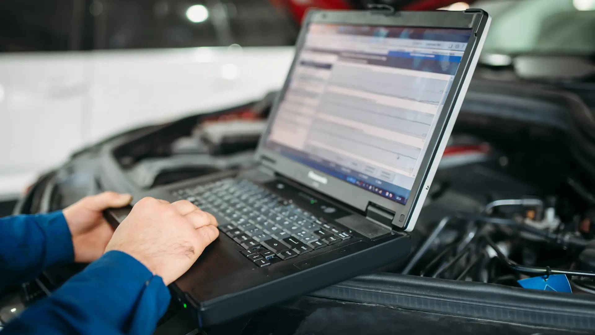 Mecanic realizând o diagnoză OBD-II la motorul mașinii, folosind un laptop pentru identificarea erorilor și verificarea sistemelor